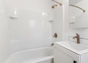 Thumbnail 36 of 66 - a white bathroom with a sink and a bath tub