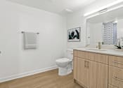 Thumbnail 26 of 54 - A white bathroom with a toilet, sink, and a picture on the wall.