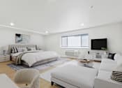 Thumbnail 25 of 54 - A modern bedroom with a large bed and a white couch.