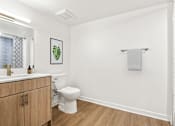 Thumbnail 46 of 54 - A white bathroom with a toilet, sink, and a picture of a leaf on the wall.