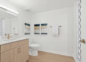 Thumbnail 30 of 54 - A bathroom with a toilet, sink, and two pictures on the wall.