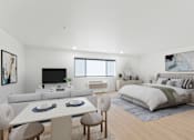 Thumbnail 28 of 54 - A modern bedroom with a large bed, a television, and a dining area with a table and chairs.