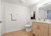 Thumbnail 34 of 54 - A white bathroom with a toilet, sink, and wooden cabinets.