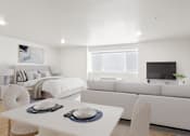 Thumbnail 33 of 54 - A modern living room with a white dining table and a white sofa.