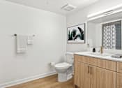 Thumbnail 39 of 54 - A bathroom with a toilet, sink, and a picture on the wall.