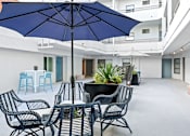 Thumbnail 15 of 54 - A blue umbrella is above a black table with chairs around it.