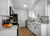 Thumbnail 1 of 19 - a kitchen with white cabinets and a bowl of fruit on the counter
