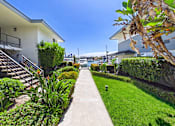 Thumbnail 24 of 251 - A white building with a balcony and a staircase is surrounded by green plants.