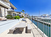 Thumbnail 22 of 251 - A marina with boats docked and a sandy area with benches.