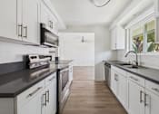 Thumbnail 5 of 251 - A kitchen with white cabinets and a black countertop.