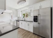 Thumbnail 2 of 251 - A modern kitchen with a stainless steel refrigerator and white cabinets.