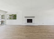 Thumbnail 6 of 251 - A large, empty room with a fireplace and wooden floors.