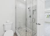 Thumbnail 14 of 251 - A white toilet sits next to a walk-in shower with a glass door.