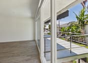 Thumbnail 16 of 251 - A balcony with a glass railing and a view of a building and trees.