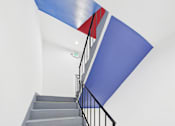 Thumbnail 30 of 32 - A staircase with a blue wall and a red and blue striped ceiling.