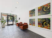 Thumbnail 31 of 32 - A hallway with a red chair and three paintings on the wall.