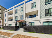 Thumbnail 25 of 32 - A modern apartment building with a black fence and a clear blue sky.
