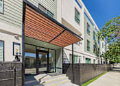 Thumbnail 26 of 32 - A modern building with a wooden awning and glass doors.