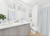 Thumbnail 33 of 52 - A bathroom with a white countertop and striped shower curtain.