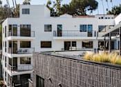 Thumbnail 14 of 119 - A modern white building with black balconies and a black wall in front.