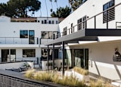 Thumbnail 17 of 119 - A modern white house with a balcony and a black railing.