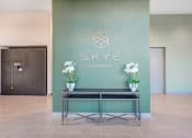 Thumbnail 15 of 26 - a lobby with a table and flowers in front of a green wall