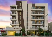 Thumbnail 7 of 26 - an apartment building with balconies and a sunset in the background