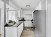 Thumbnail 1 of 11 - an empty kitchen with white cabinets and a stainless steel refrigerator