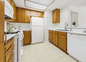 Thumbnail 1 of 17 - A kitchen with white appliances and wooden cabinets.