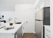 Thumbnail 16 of 82 - A kitchen with a white counter top and a black refrigerator.