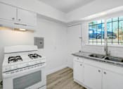 Thumbnail 19 of 20 - a white kitchen with a stove and a sink