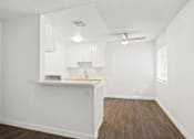 Thumbnail 14 of 38 - an empty living room and kitchen with white cabinets and wood flooring