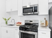 Thumbnail 8 of 25 - a kitchen with white cabinetry and stainless steel appliances