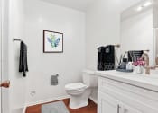 Thumbnail 15 of 25 - a bathroom with white walls and wood floors and a white toilet next to a sink with a