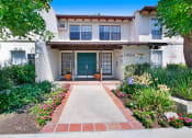 Thumbnail 14 of 16 - a walkway in front of a white building with a blue door