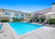 Thumbnail 16 of 16 - a swimming pool with lounge chairs and umbrellas in front of a building