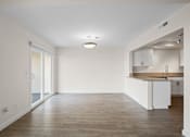Thumbnail 14 of 208 - A spacious room with a kitchen area and wooden flooring.