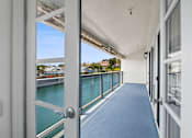 Thumbnail 30 of 208 - A white door opens to a balcony with a view of a body of water.