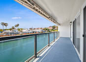Thumbnail 31 of 208 - A long hallway with a view of a body of water and palm trees.