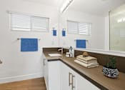 Thumbnail 16 of 228 - A bathroom with a white sink and a brown counter.