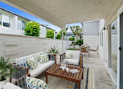 Thumbnail 9 of 228 - A patio with a white couch and a wooden table.