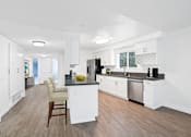 Thumbnail 4 of 228 - A kitchen with white cabinets and a wooden floor.