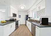 Thumbnail 3 of 228 - A modern kitchen with white cabinets and stainless steel appliances.