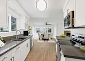 Thumbnail 2 of 228 - A modern kitchen with white cabinets and a wooden floor.