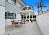 Thumbnail 10 of 228 - A patio with a table and chairs is surrounded by white walls.
