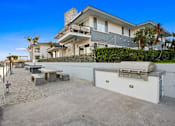 Thumbnail 167 of 208 - A modern house with a sandy outdoor area and a grill.