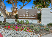 Thumbnail 162 of 208 - A sign for Waterfront Newport Beach Residences & Marina is displayed in front of a landscaped area.