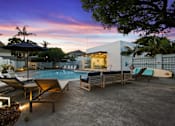 Thumbnail 192 of 208 - A poolside area with lounge chairs and a surfboard.