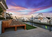 Thumbnail 201 of 208 - A wooden bench sits on a concrete patio overlooking a marina with boats.