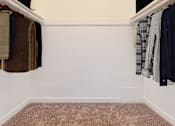 Thumbnail 14 of 23 - a closet with clothes hanging on the wall and a carpet